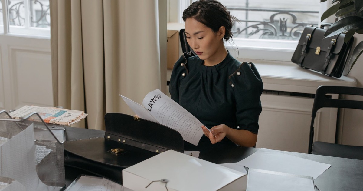 Elegant young woman reading documents in a stylish office setting.