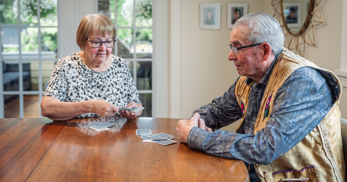 Senior couple playing cards at home, fostering connection and fun.