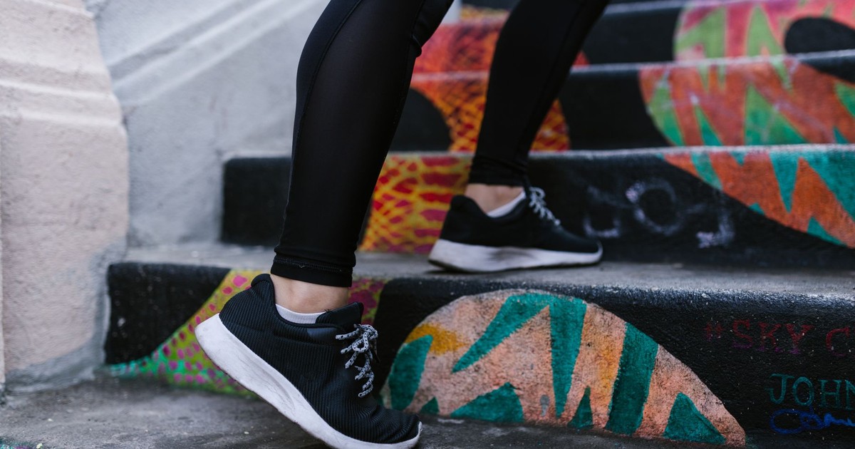 Close-up of a person walking up colorful graffiti stairs wearing sneakers.