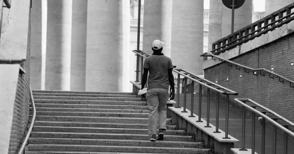 A person walking up an urban stairway captured in black and white, emphasizing structure.