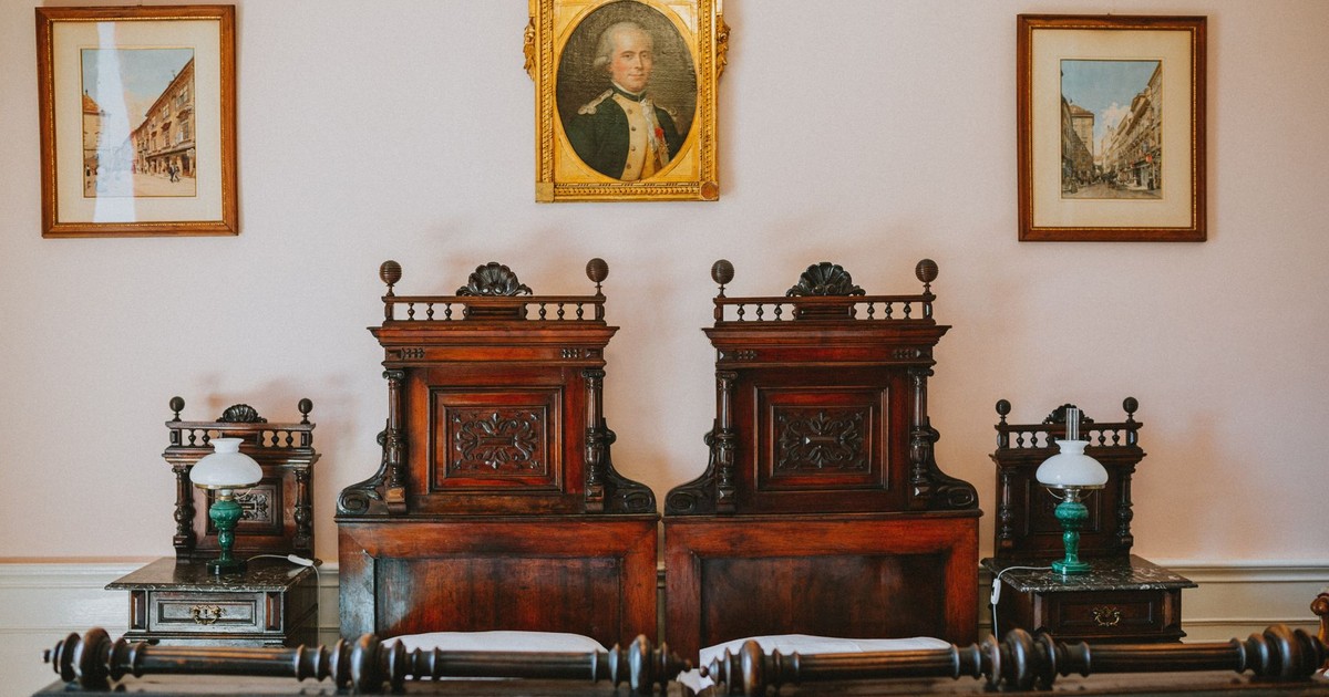 Vintage room with antique twin beds and wooden decor, highlighting 19th-century design.
