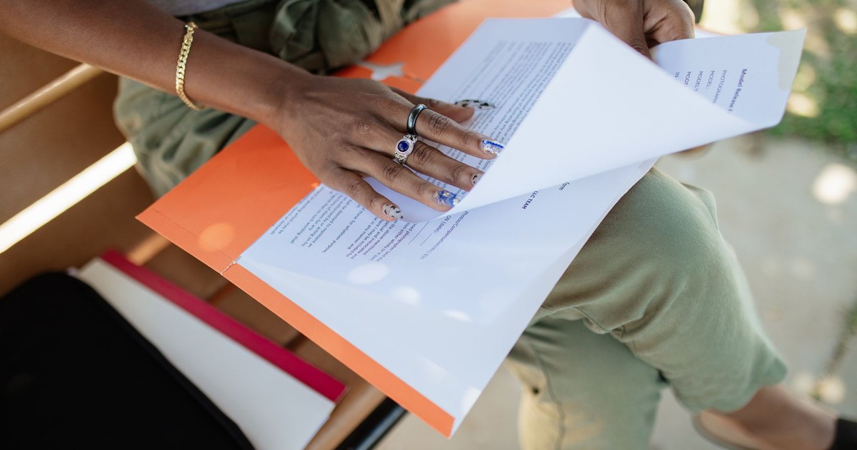 Close-up of a woman checking documents on a bench in natural light.