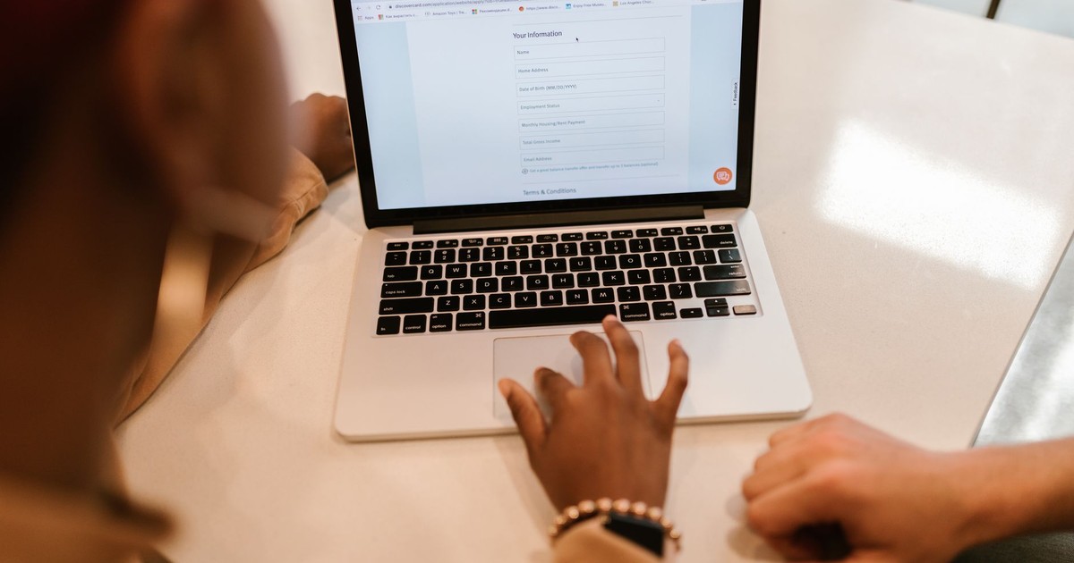 Two adults working together on a laptop displaying an online form, indoors.