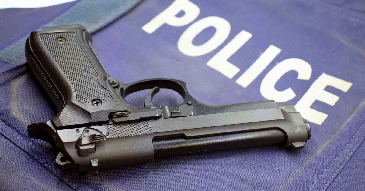 A black pistol resting on a police vest, highlighting law enforcement gear.