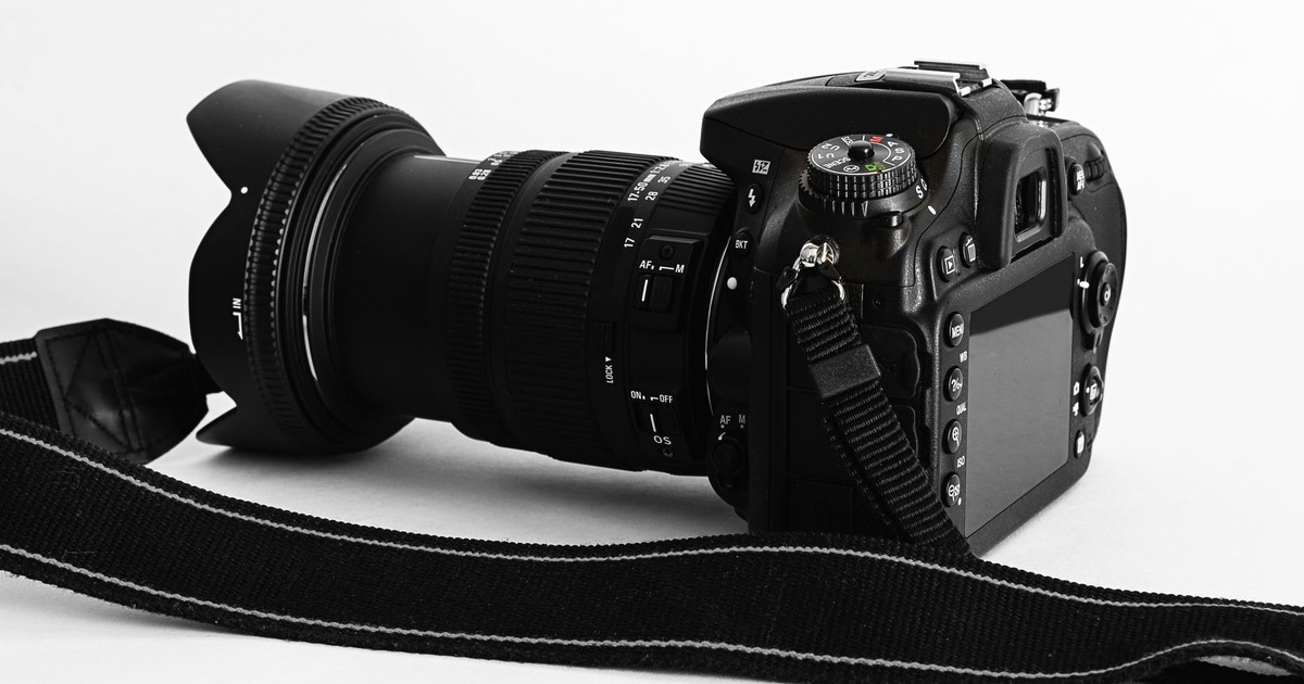 Close-up of a DSLR camera with lens and strap on a white background.