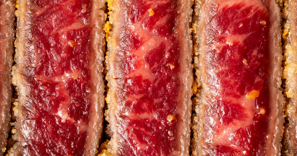 Detailed close-up of raw beef cutlet with a crispy coating texture.