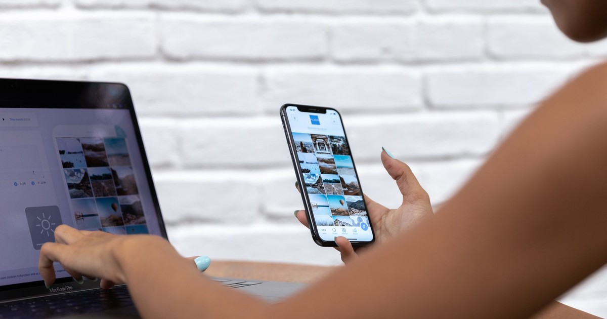 A woman working remotely using a laptop and smartphone, focusing on social media content.