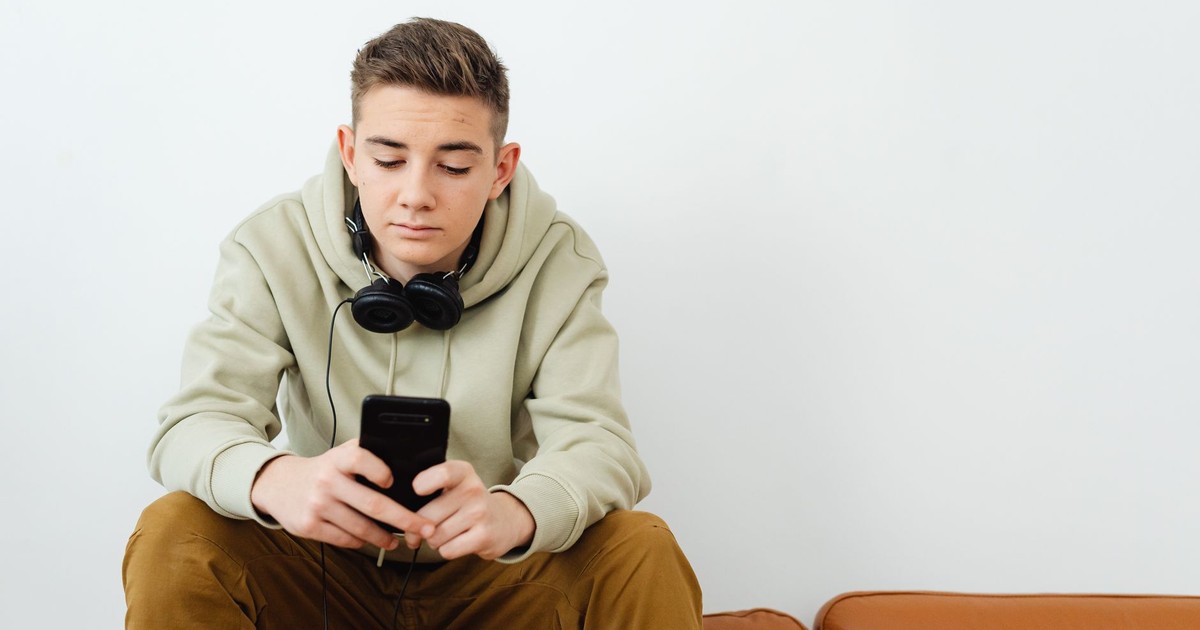 Young adult chilling with smartphone and headphones on a couch in a relaxed vibe.