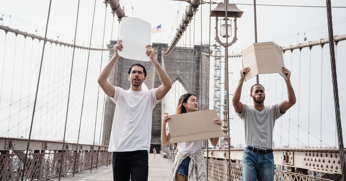 A diverse group of protesters holding blank placards on the Brooklyn Bridge, USA.