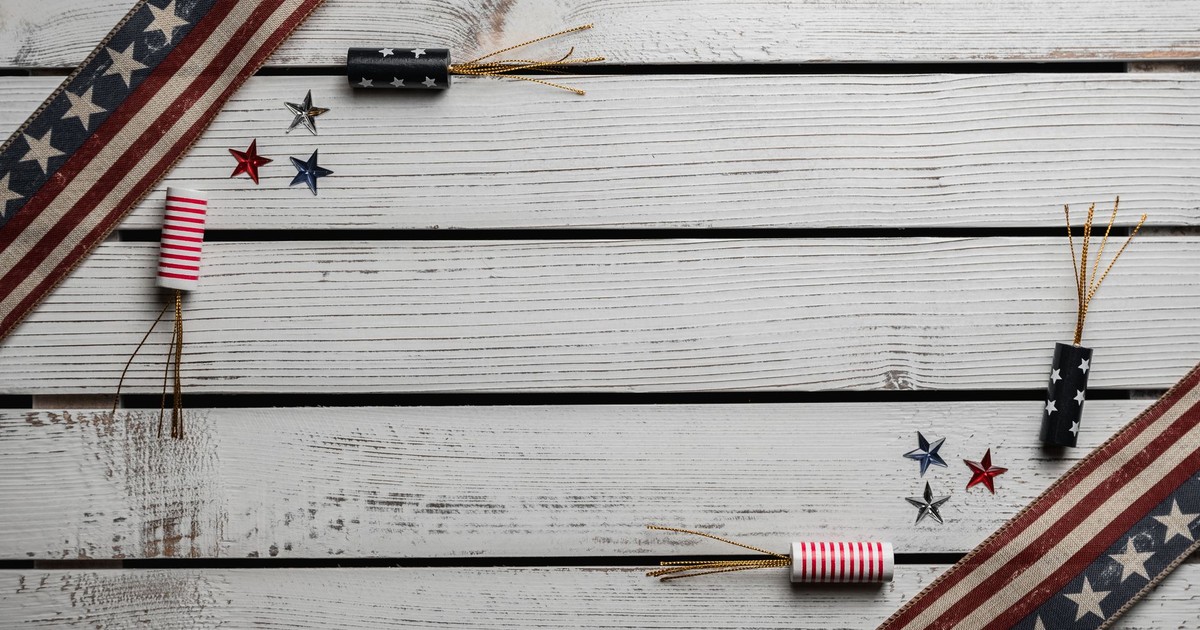 From above of fireworks and tiny multi colored stars between long narrow Flags of United States at angle