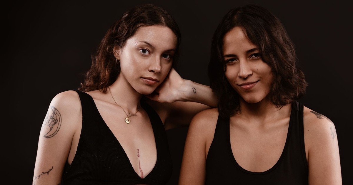 Fashion portrait of two women with tattoos in a studio setting.