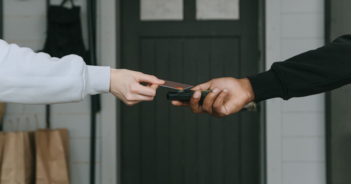 Close-up of hands making a contactless card payment indoors, highlighting cashless transaction technology.