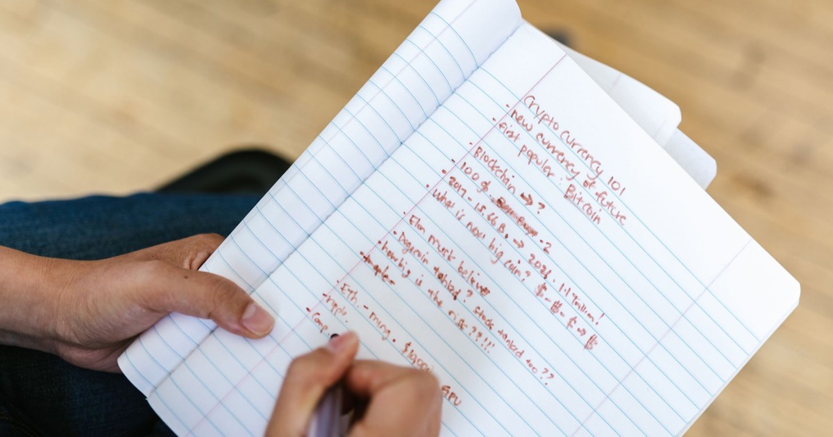 A person writing cryptocurrency notes in a notebook, highlighting Bitcoin and future predictions.