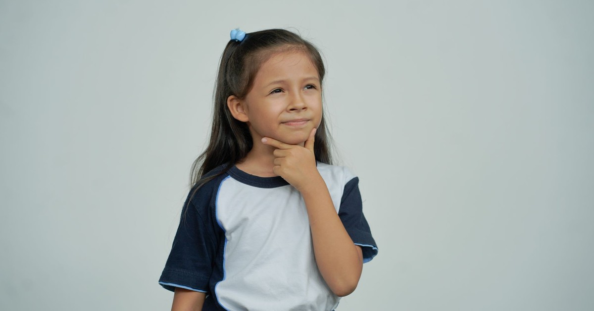 A young girl in casual attire thoughtfully posing against a white background in a studio setting.