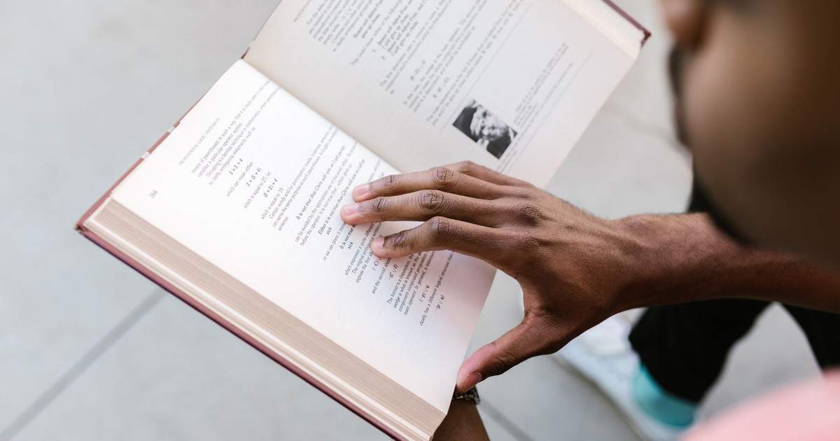 A man engrossed in reading an open book, highlighting education and learning.