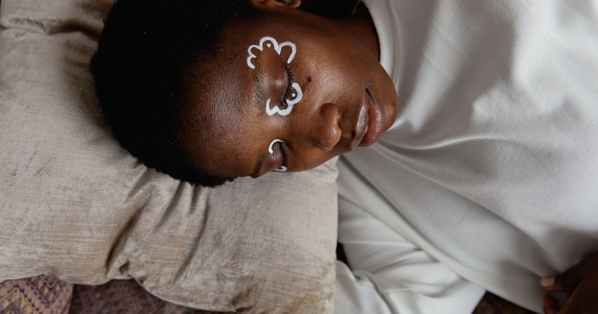Calm woman resting in bed with eye cream, exuding tranquility and relaxation.