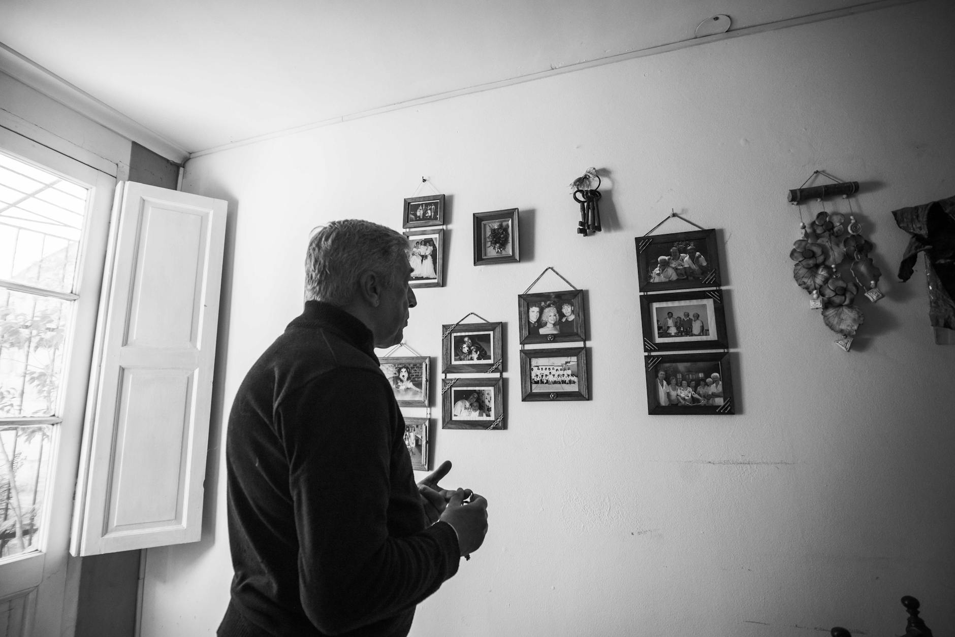 A man observing family photos on a wall captures nostalgia and connection.