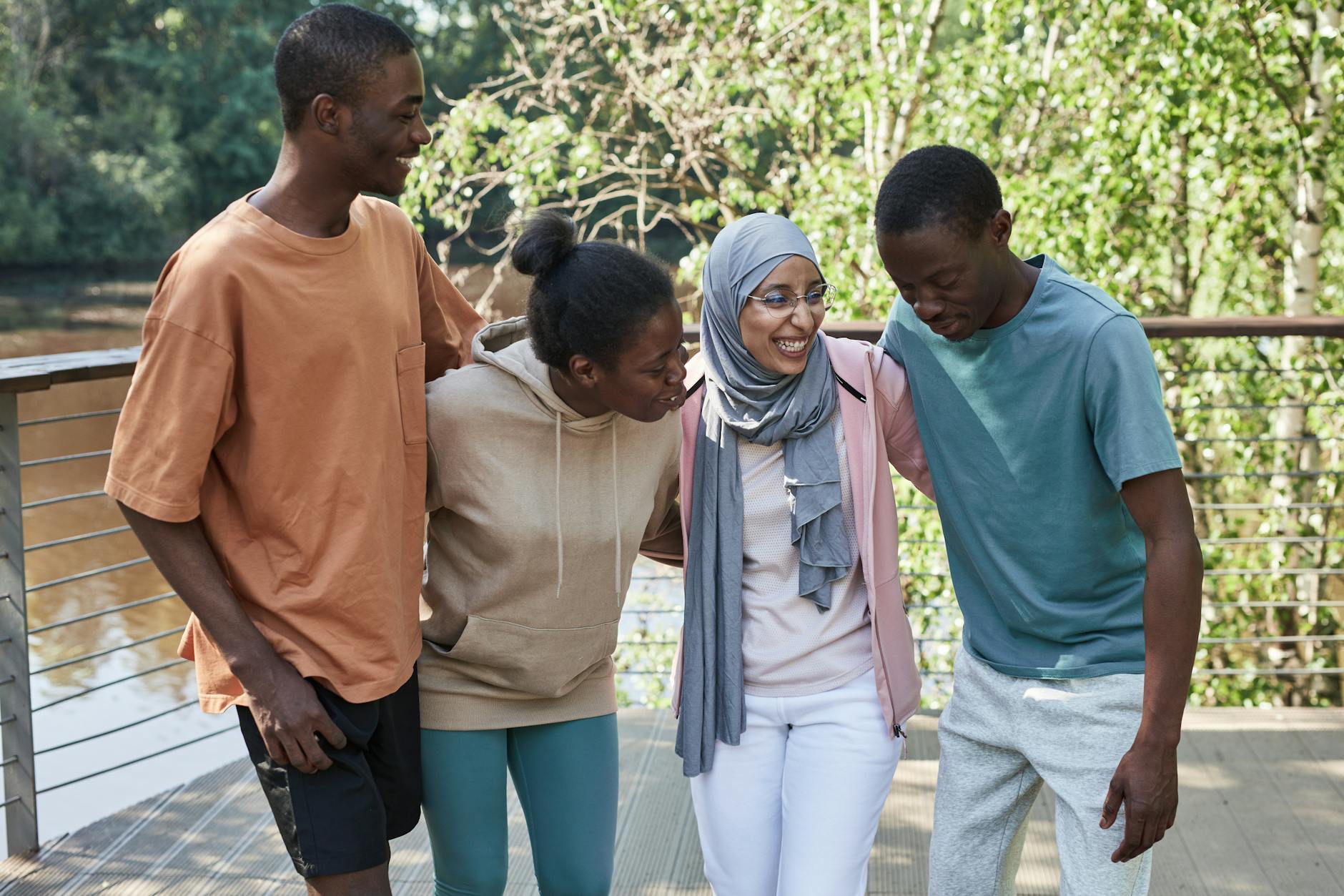Four diverse friends share laughter and happiness outdoors on a sunny day.