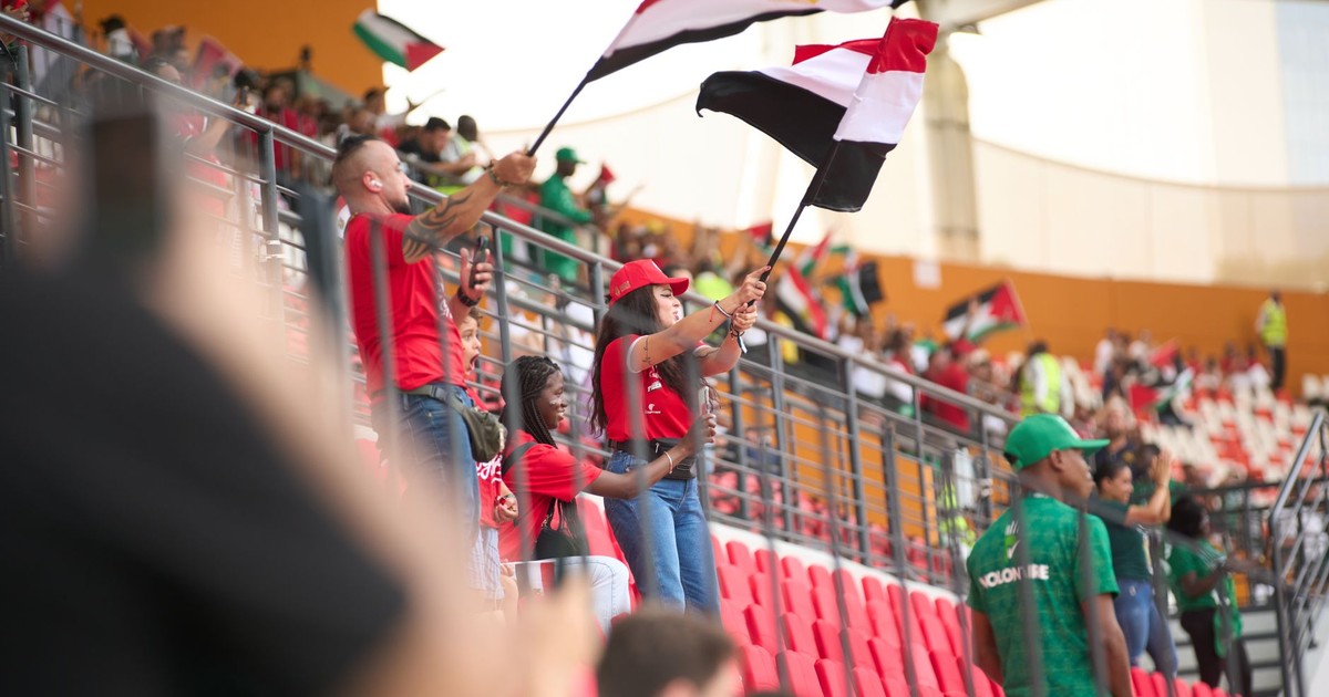Soccer fans in the stadium wave Egyptian flags, showing their support during a lively sports match.