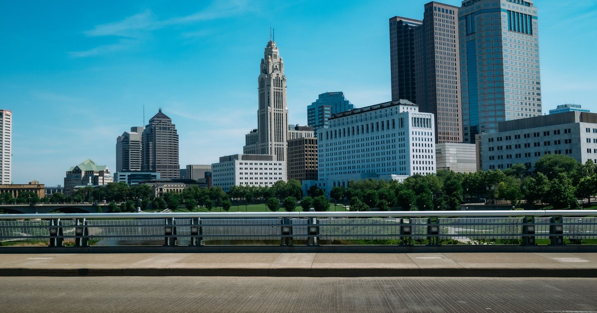 View of Columbus skyline featuring high-rise buildings against a blue sky, with urban trees.