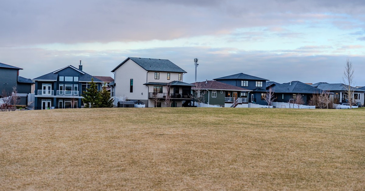 A view of suburban homes overlooking a vast open field under a partly cloudy sky.