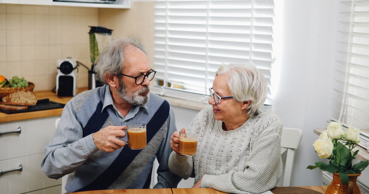 Senior couple enjoying coffee together at home in cozy kitchen setting.