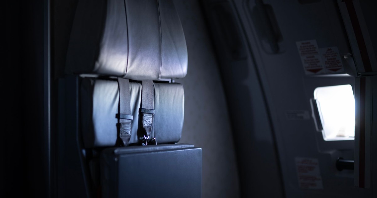 Moody view of an airplane interior focusing on the emergency exit with low lighting.