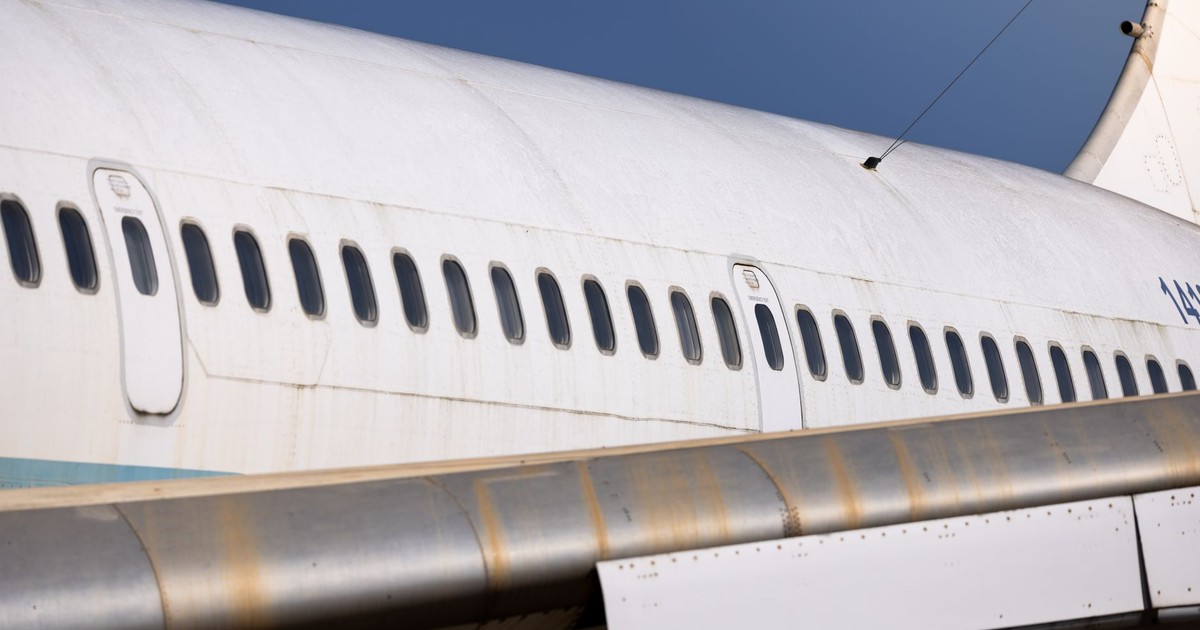 Detailed view of an airplane fuselage showing windows and wing in bright daylight.