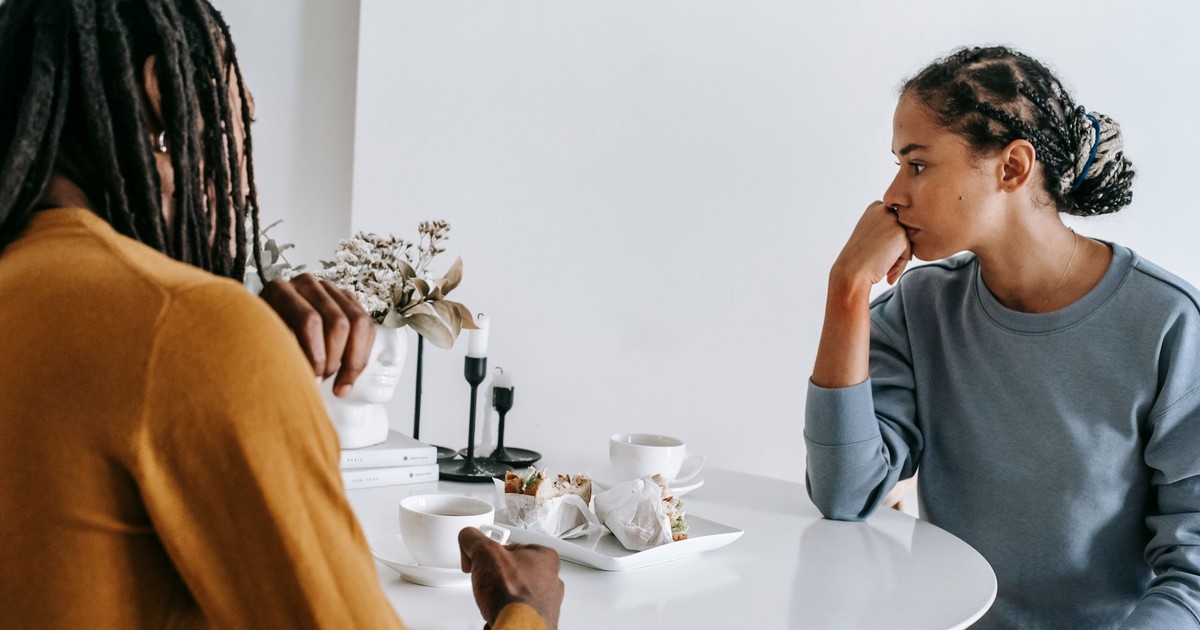 Young African American man sitting with woman at table and having conflict with each other at home