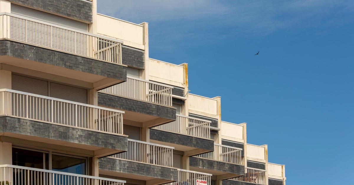 A modern apartment building with distinct balconies against a clear blue sky.