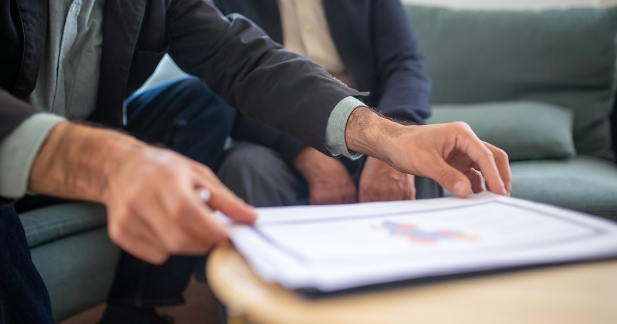 Two men discussing documents during a business meeting, focusing on paperwork.