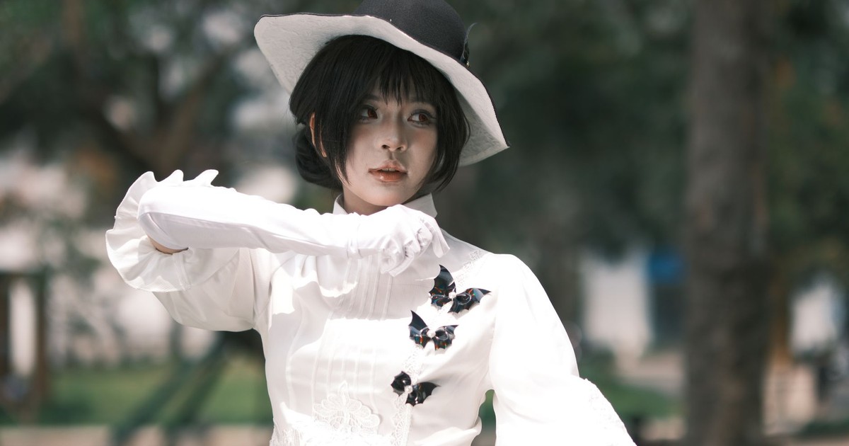 Young woman dressed in white with Victorian style hat and gloves, exuding elegance outdoors.