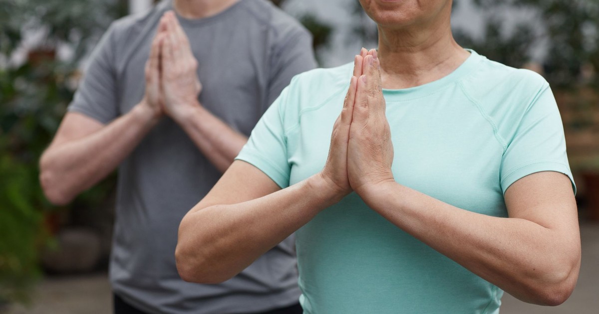 Senior couple in a meditative yoga pose outdoors, promoting wellness and a healthy lifestyle.
