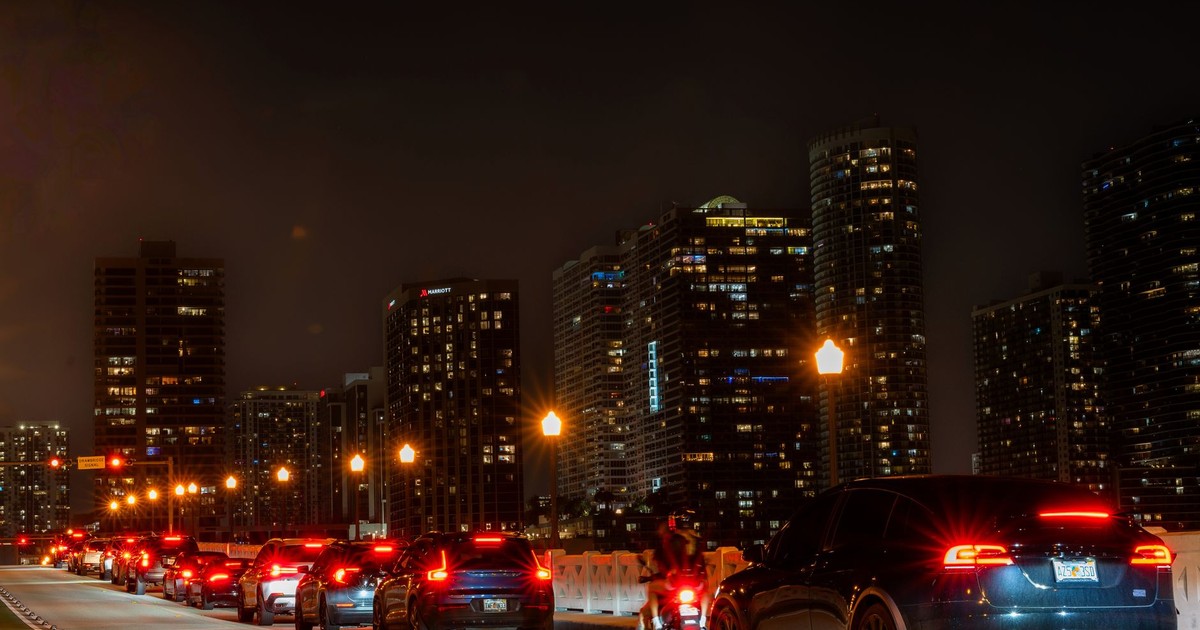 City skyline at night with traffic lights and cars on a busy urban street.