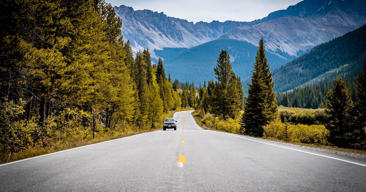 A scenic drive through the Rocky Mountains with a winding road and pine trees.