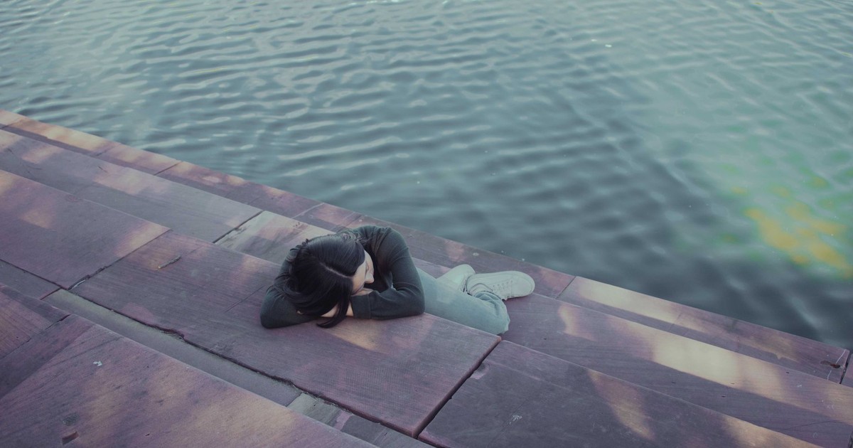 A woman rests peacefully by the water, embodying serenity and calm in Austin, Texas.