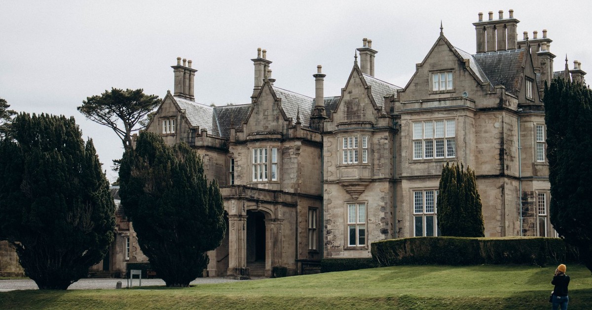 Historic Muckross House in Killarney, Ireland, surrounded by lush greenery.
