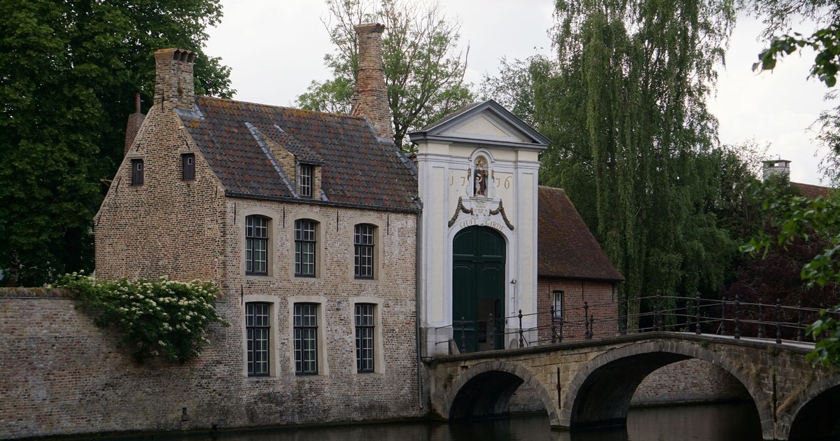 Quaint medieval buildings along the serene canal in Bruges, Belgium, showcasing historic architecture.