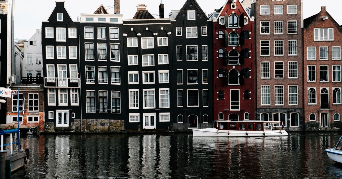 Stunning view of Amsterdam's iconic canal houses reflecting on water, showcasing unique architecture.