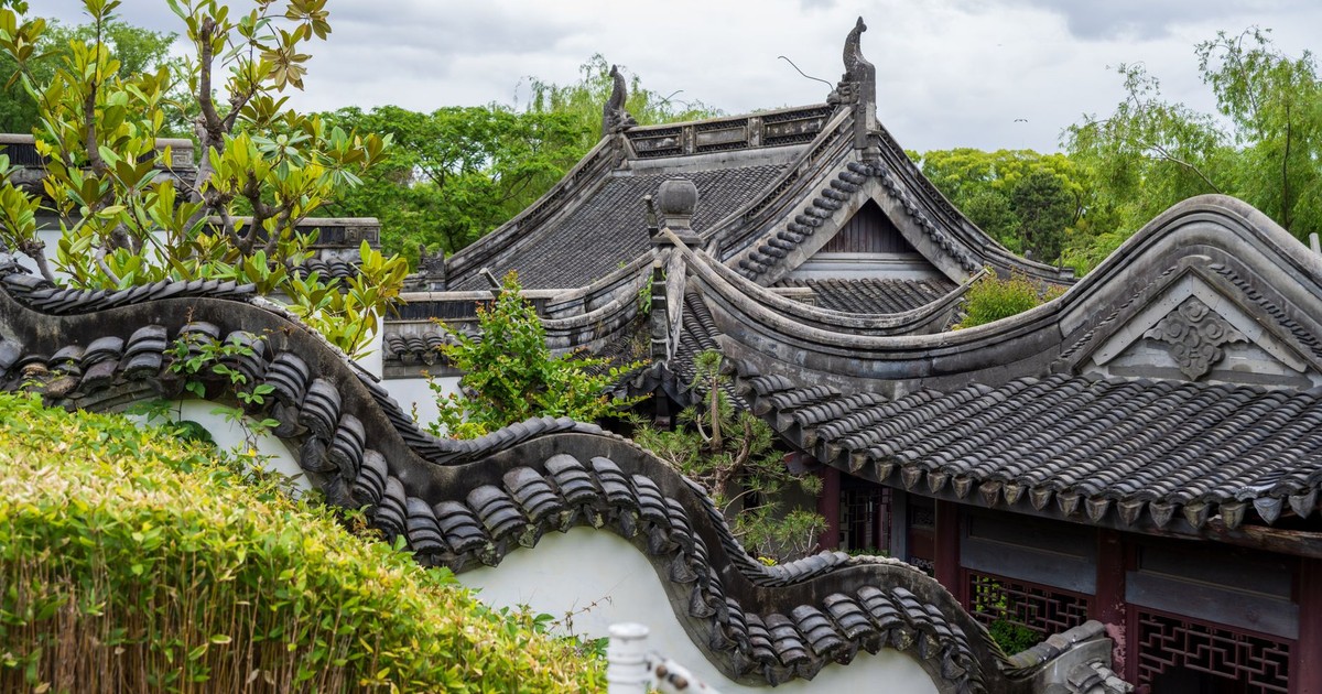 Captivating view of traditional Chinese garden architecture featuring intricate curved roofs amidst lush greenery.