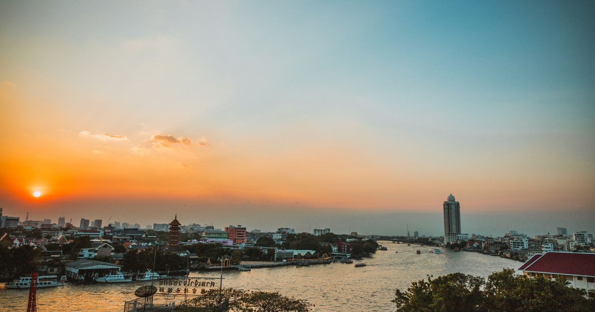 Stunning sunset view over Bangkok's Chao Phraya River with cityscape and skyline.