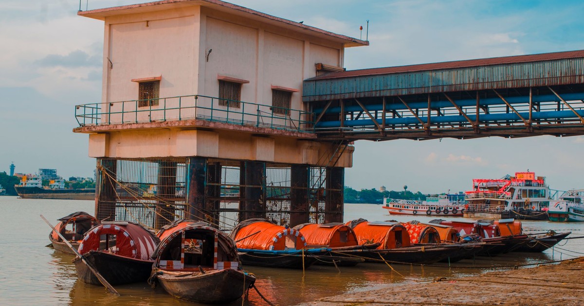 Wooden boats moored on the Ganges Riverbank next to a pier building in India.