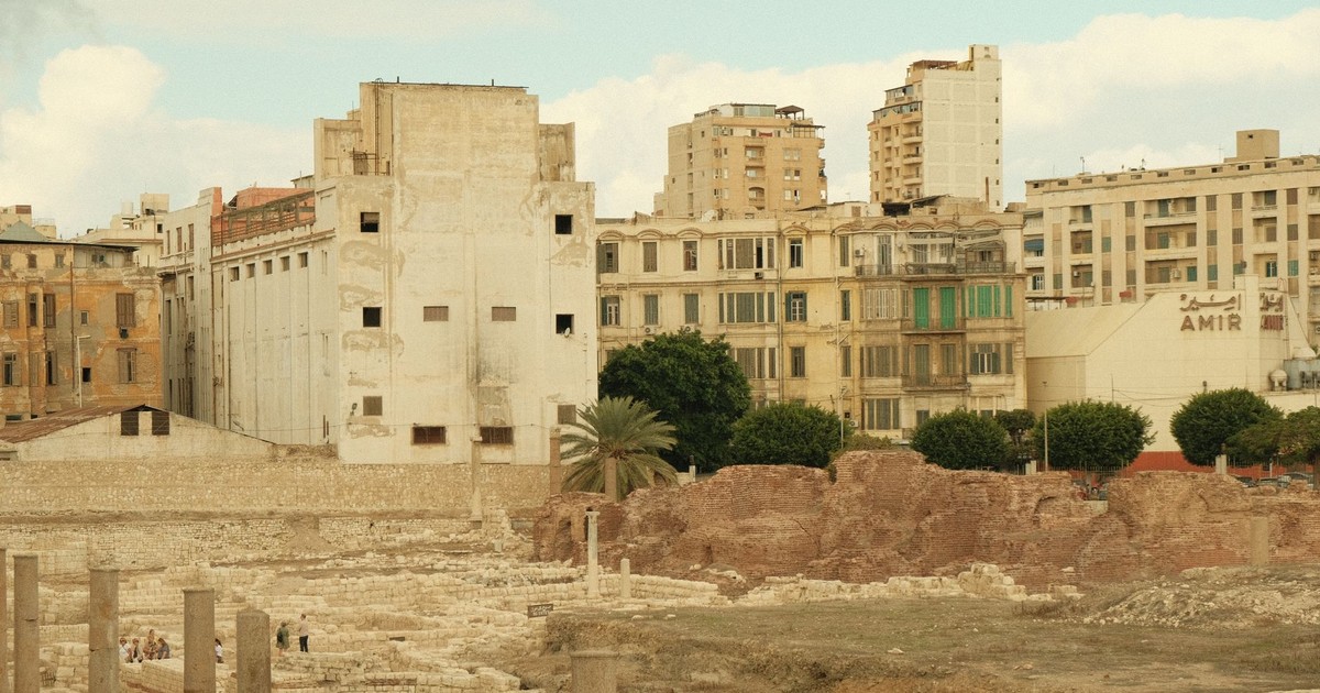 View of ancient Roman ruins against a modern urban backdrop, capturing history's blend with contemporary architecture.