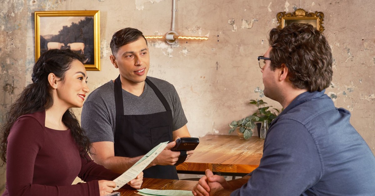 Server uses handheld POS for efficient customer service in a modern restaurant.