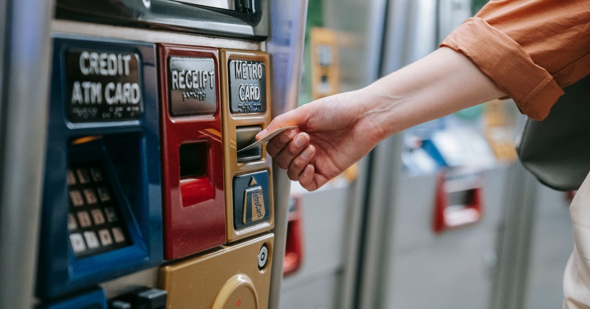Close-up of a person using a metro card machine for public transport payment indoors.