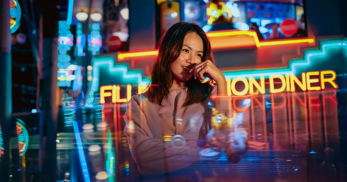 Captivating photo of a woman in a neon-drenched diner setting, exuding a modern, stylish vibe.