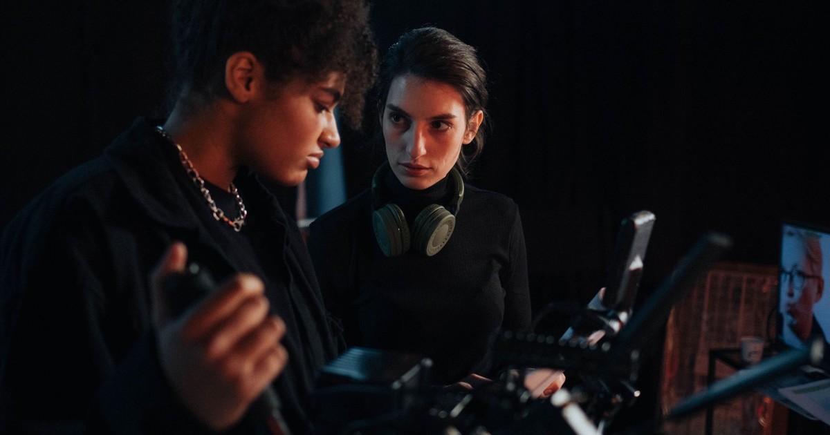 Two filmmakers collaborating on a project in a dark studio setting.