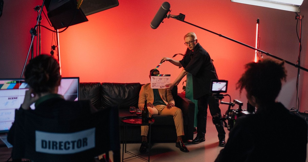 A behind-the-scenes look at a filming crew setting up a scene indoors with lighting equipment.
