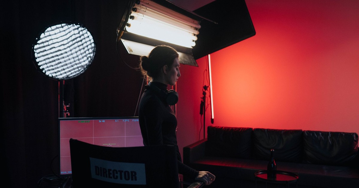 A director in a studio setting with lighting and equipment, creating a cinematic atmosphere.