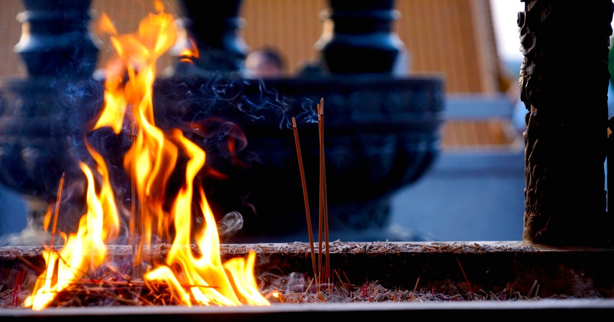 Close-up of incense sticks burning with vibrant flames at a temple.